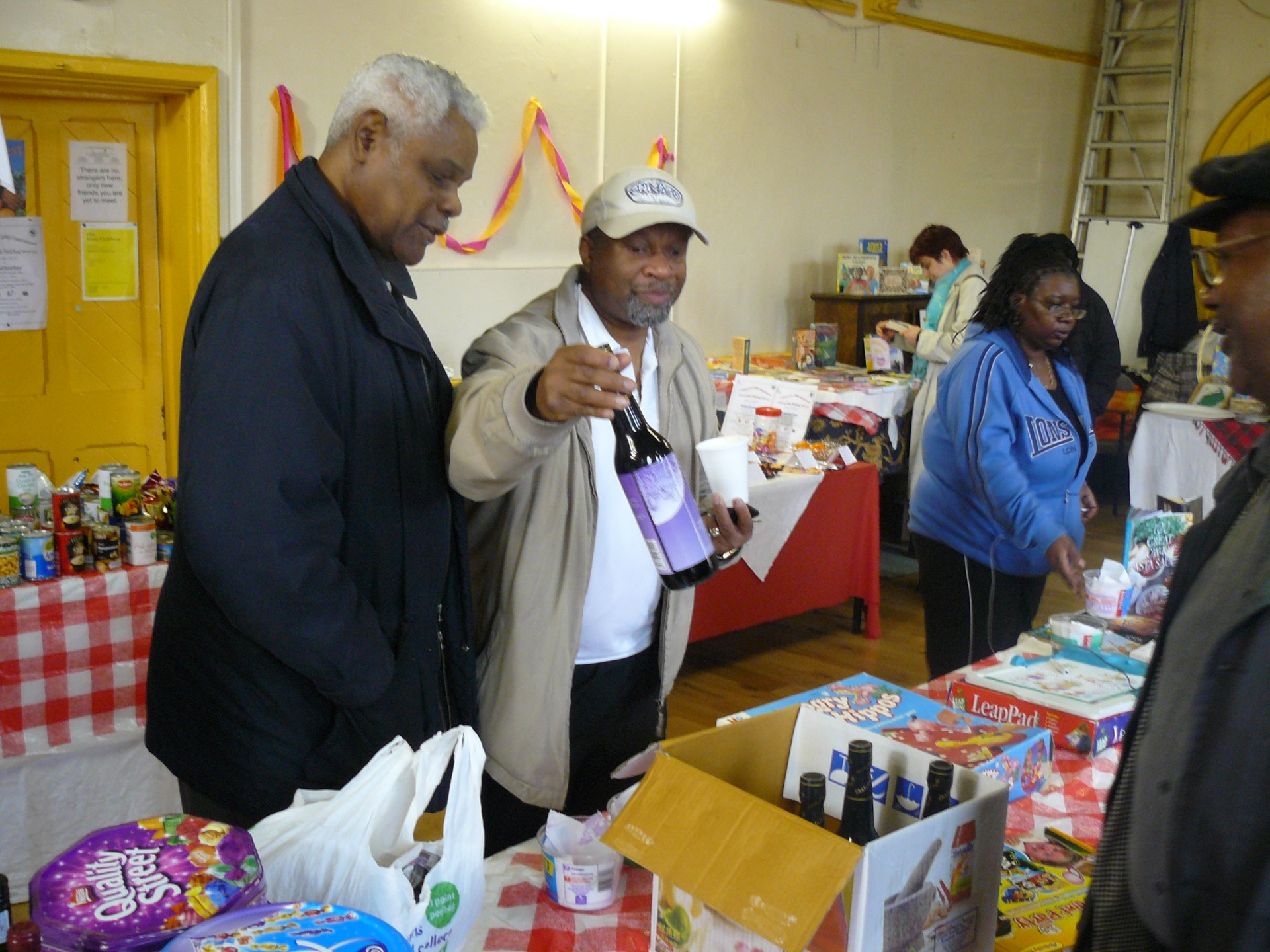 People standing in a church hall event looking at the items on a table