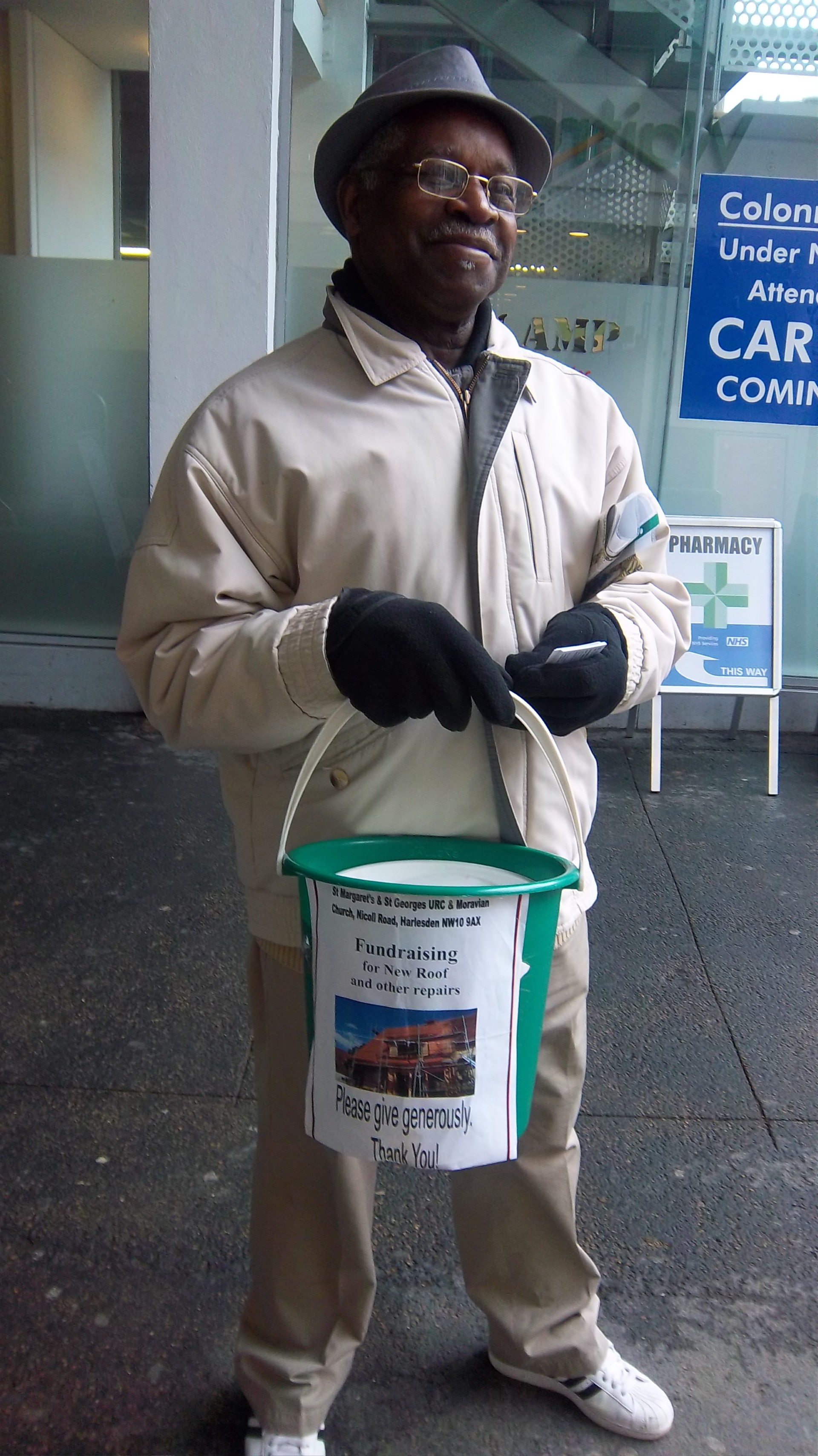 A man holding a collection bucket to fundraising for a new roof and other repairs for the church